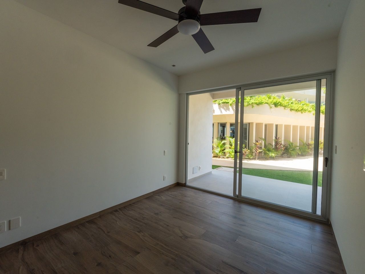 Bedroom with a sliding glass door open to a landscaped garden walkway at The Leaf