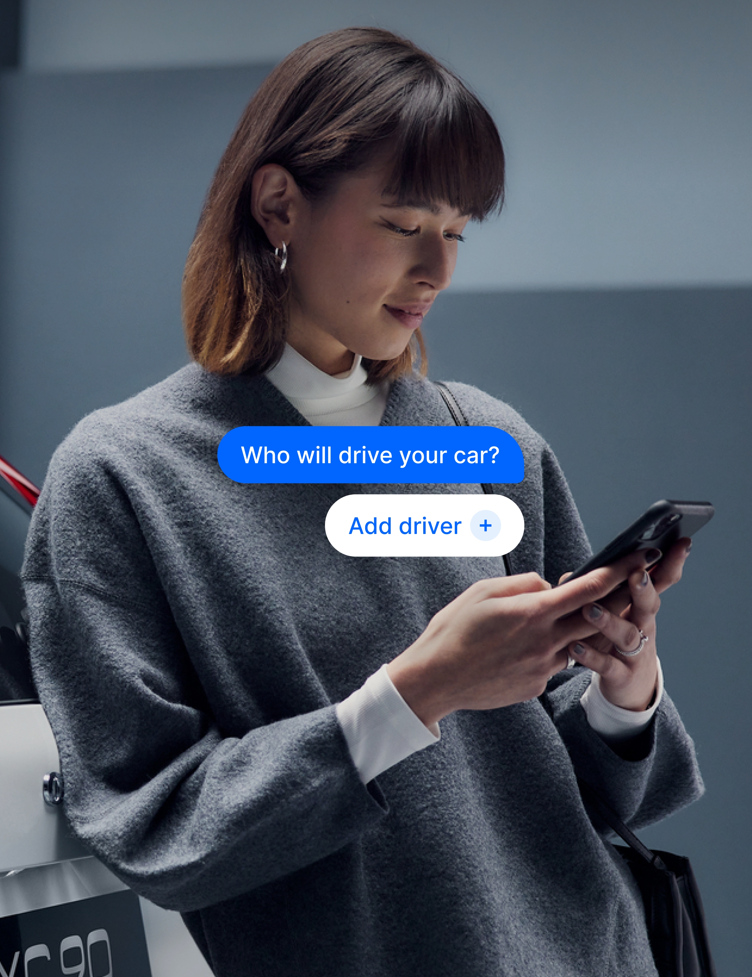 Person standing next to a car, using a smartphone, with an app interface asking, “Who will drive your car?”