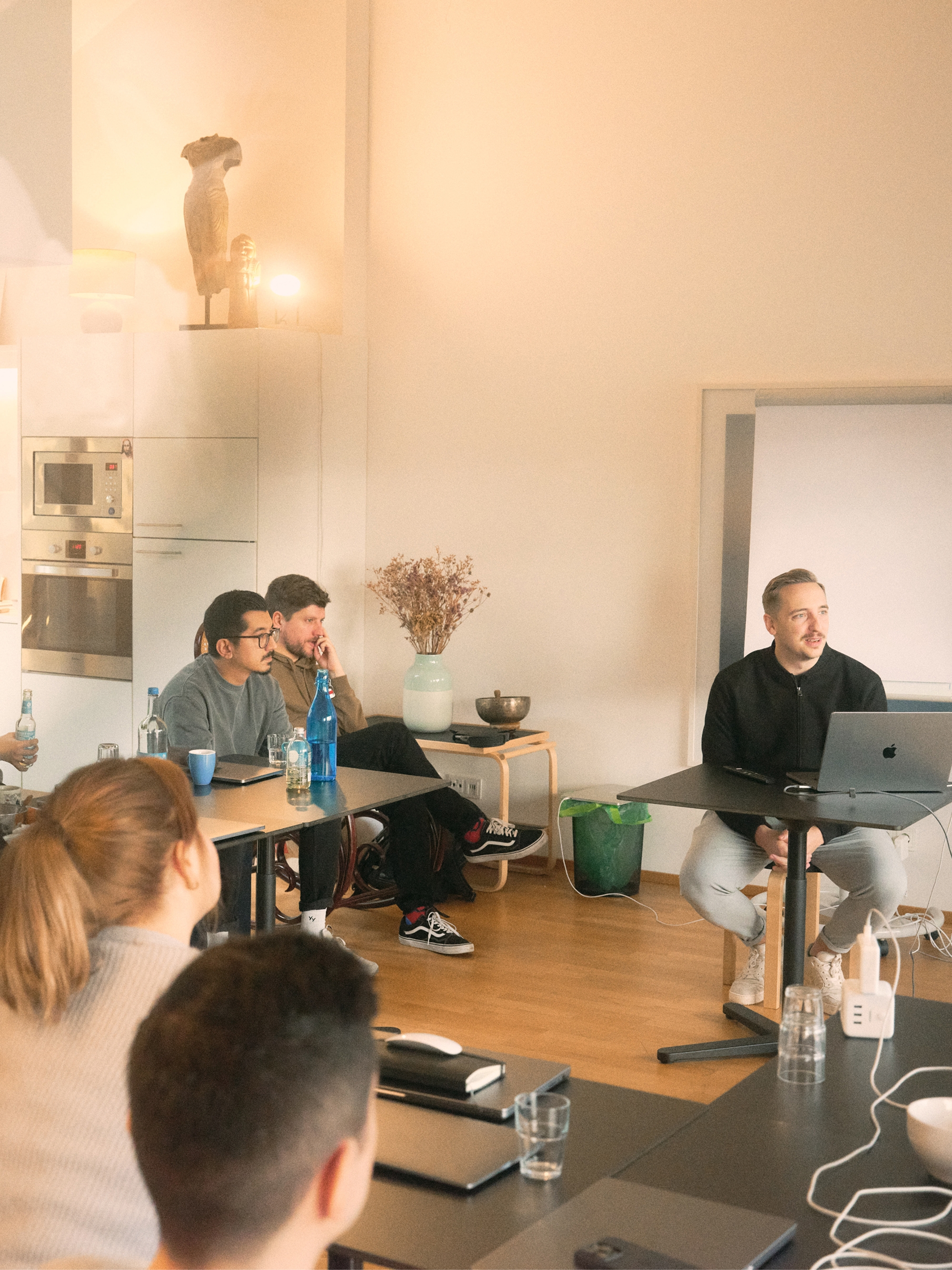 Group of people attending a meeting or presentation in a room with a presenter using a laptop