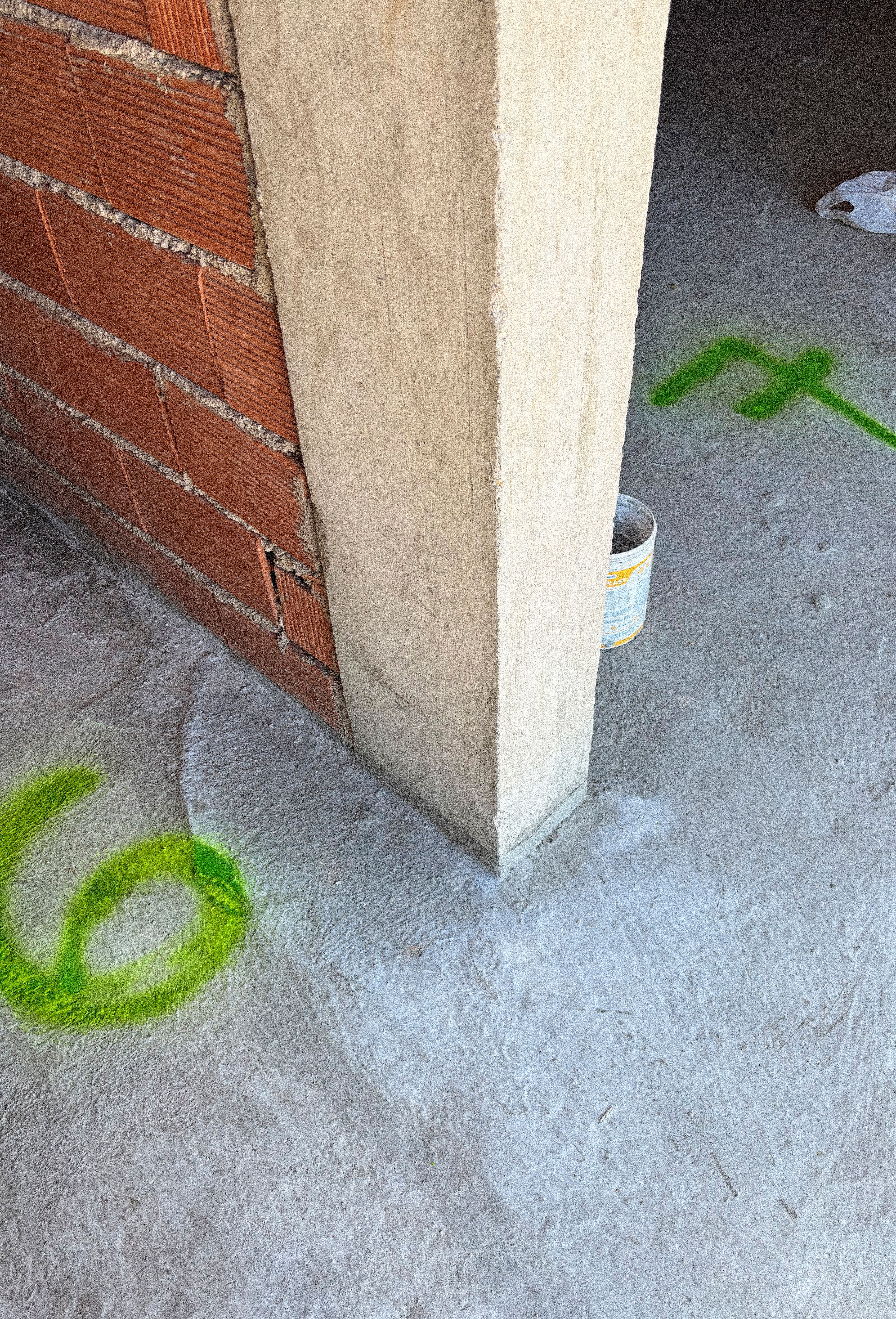 Columna de hormigón y muro de ladrillo con marcas de obra en PSMA.