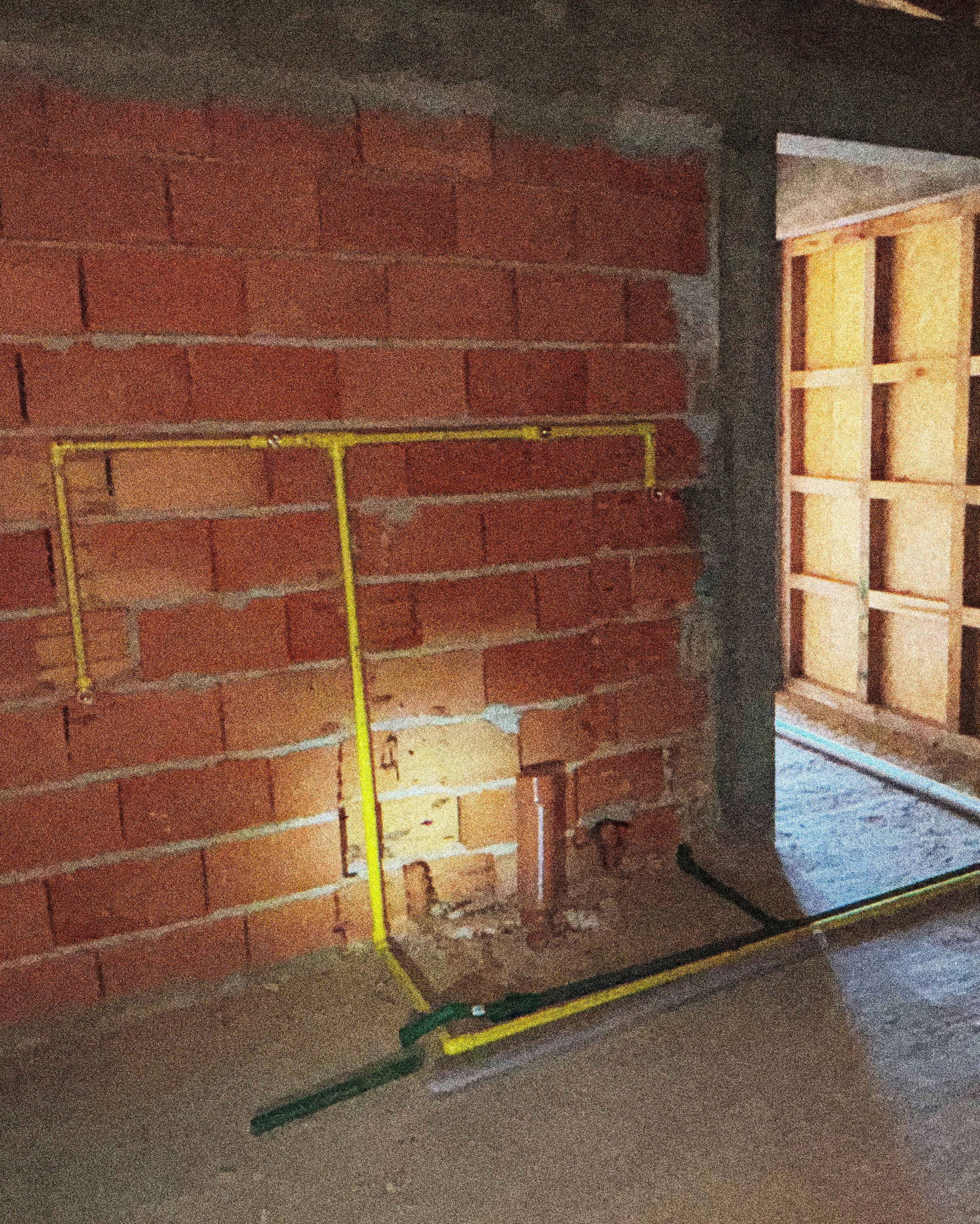 Muro de ladrillo con instalaciones de gas a la vista durante la obra de PSMA.