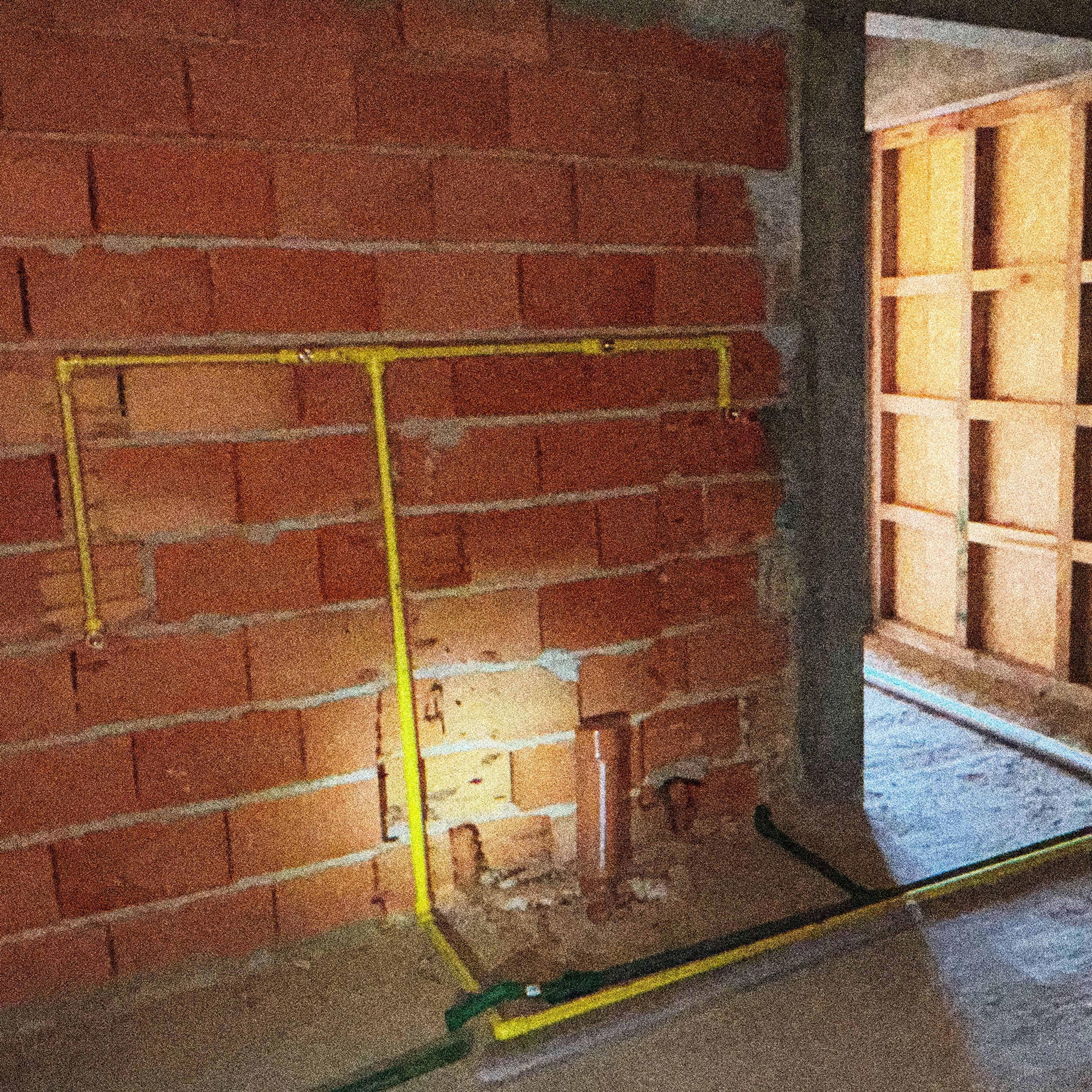 Muro de ladrillo con instalaciones de gas a la vista durante la obra de PSMA.