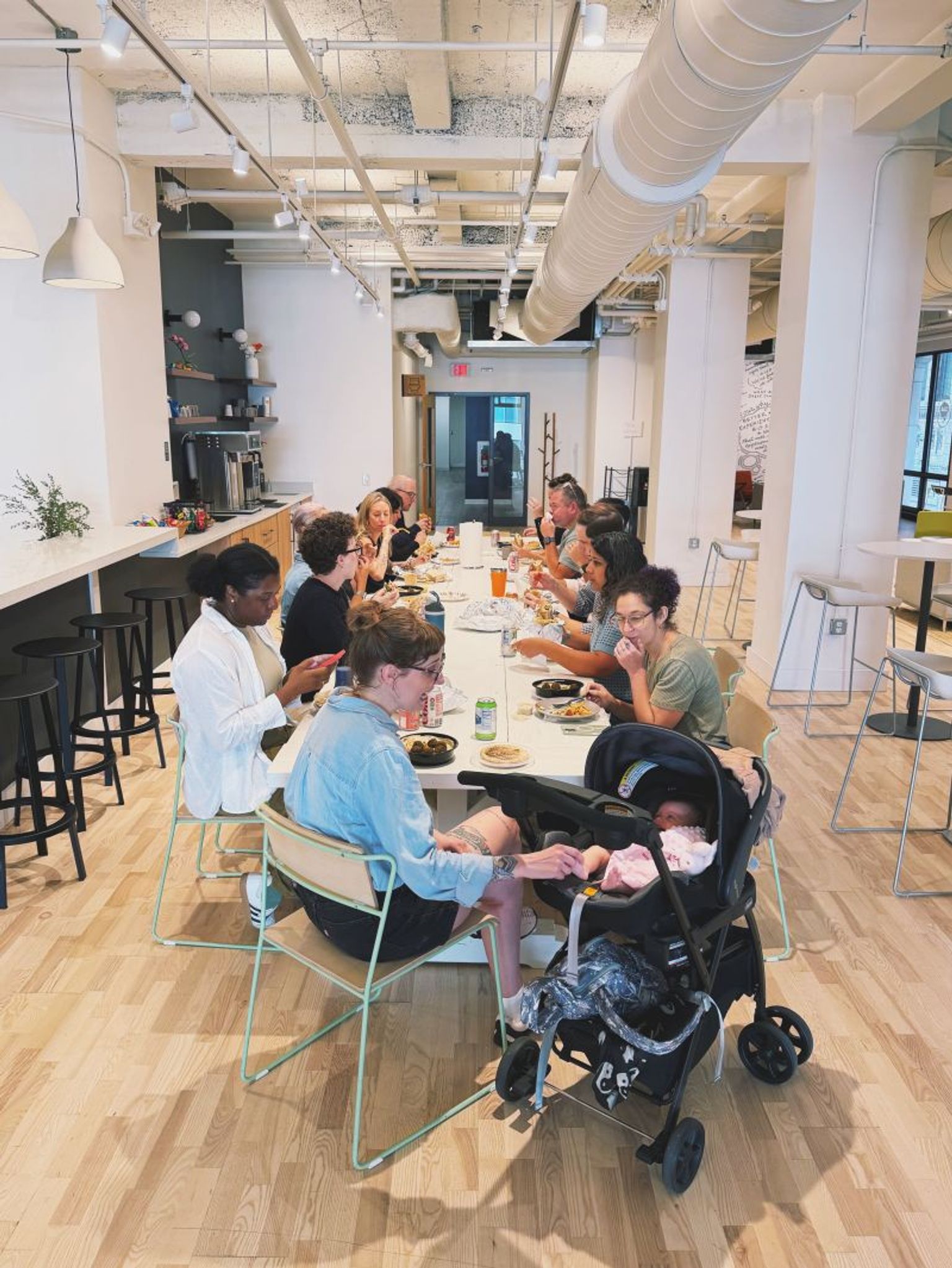 Coworkers having lunch together a long lunch table at Think Company