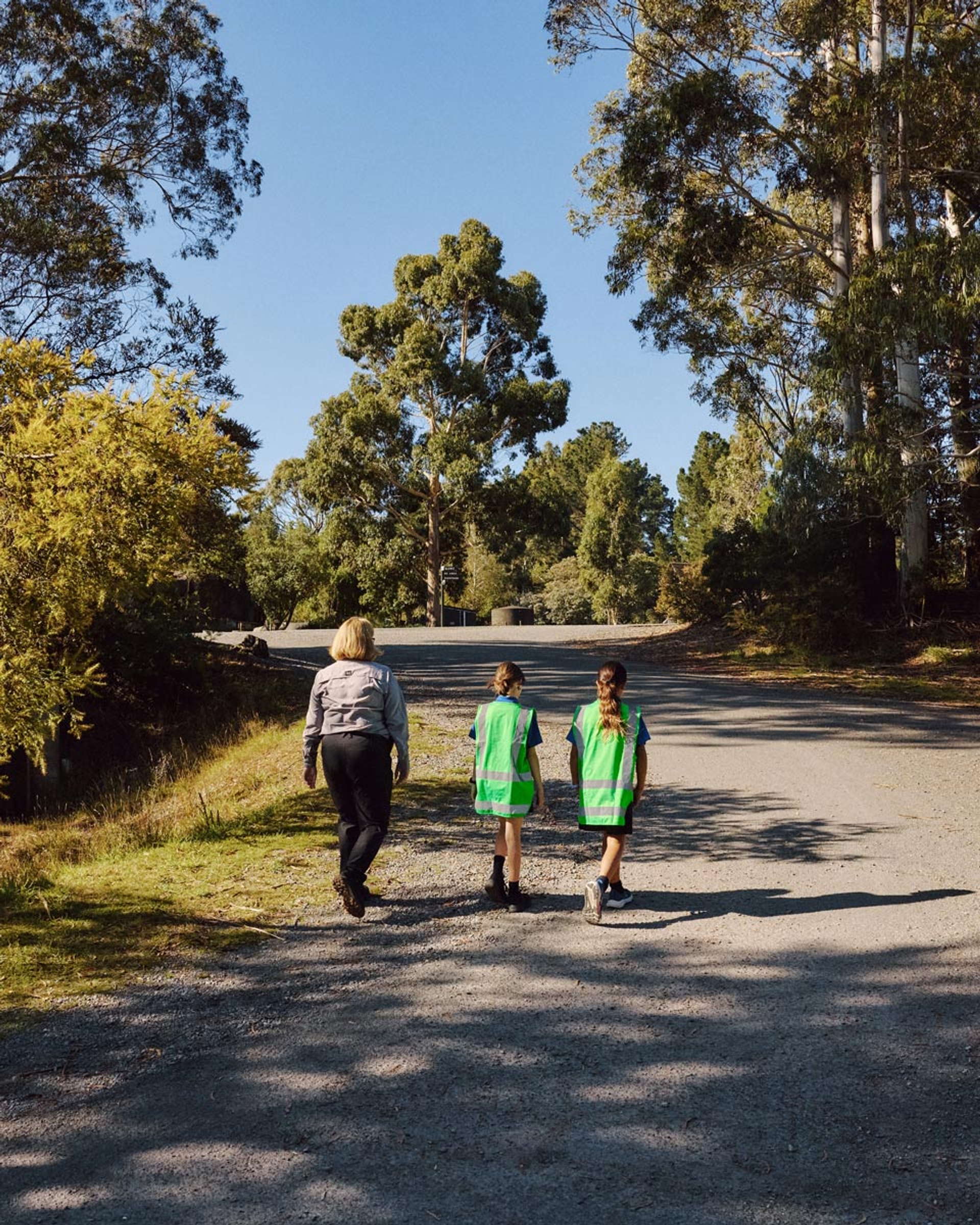 Children in hi-vis vests walking through the Park with an adult