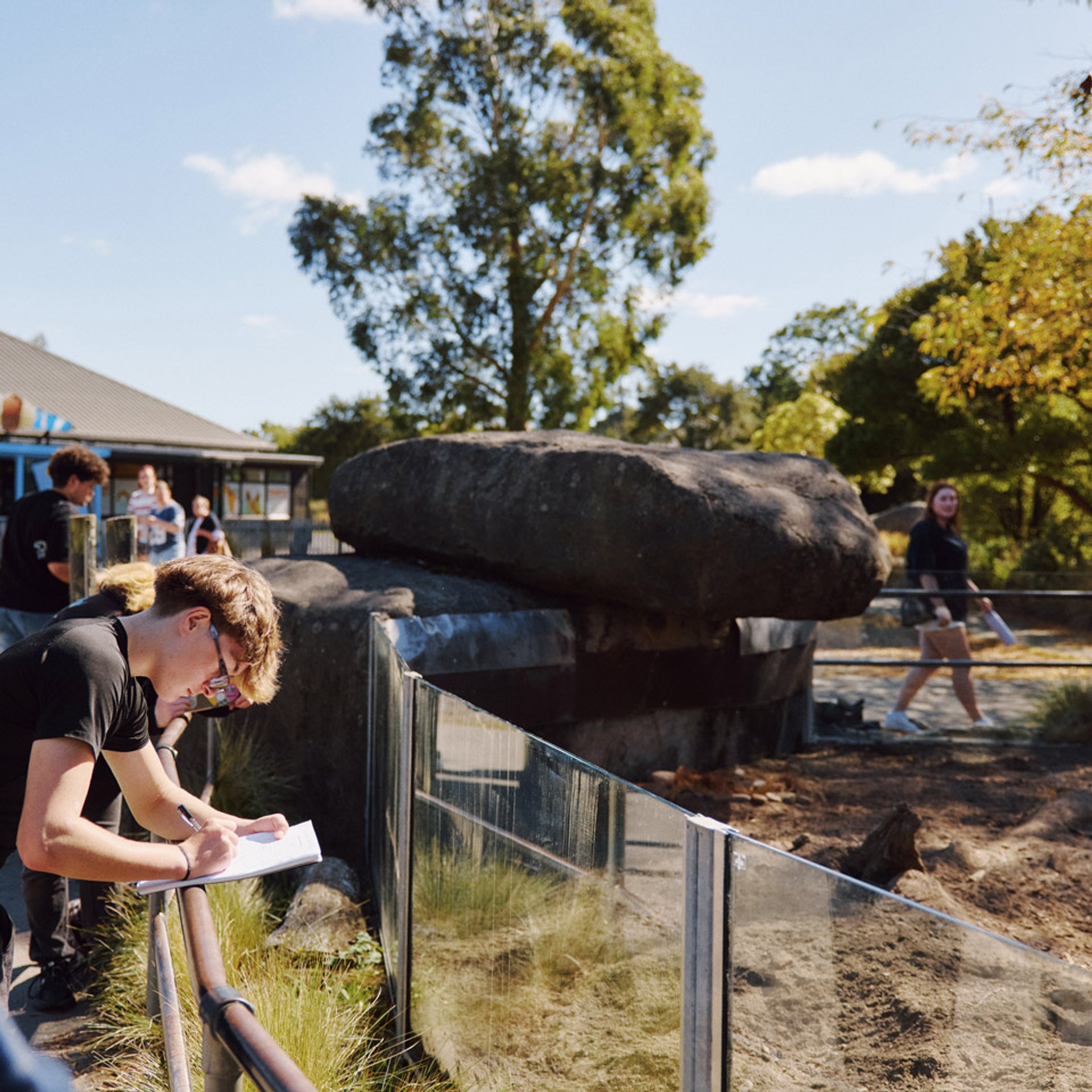 A student taking notes at an enclosure railing