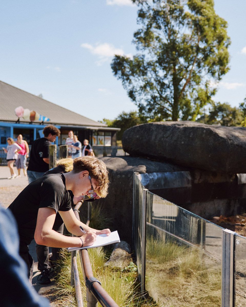 A student writing notes on a clipboard beside an enclosure