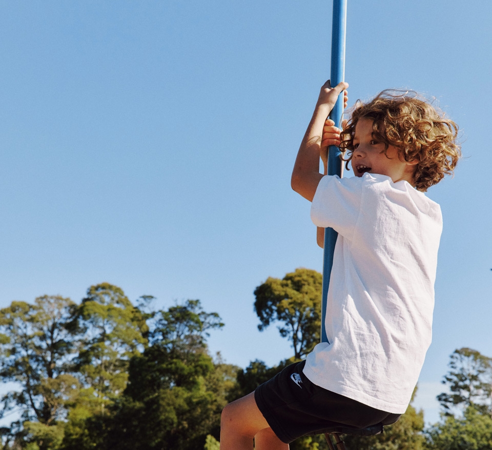 A boy swinging on a flying fox in the playground