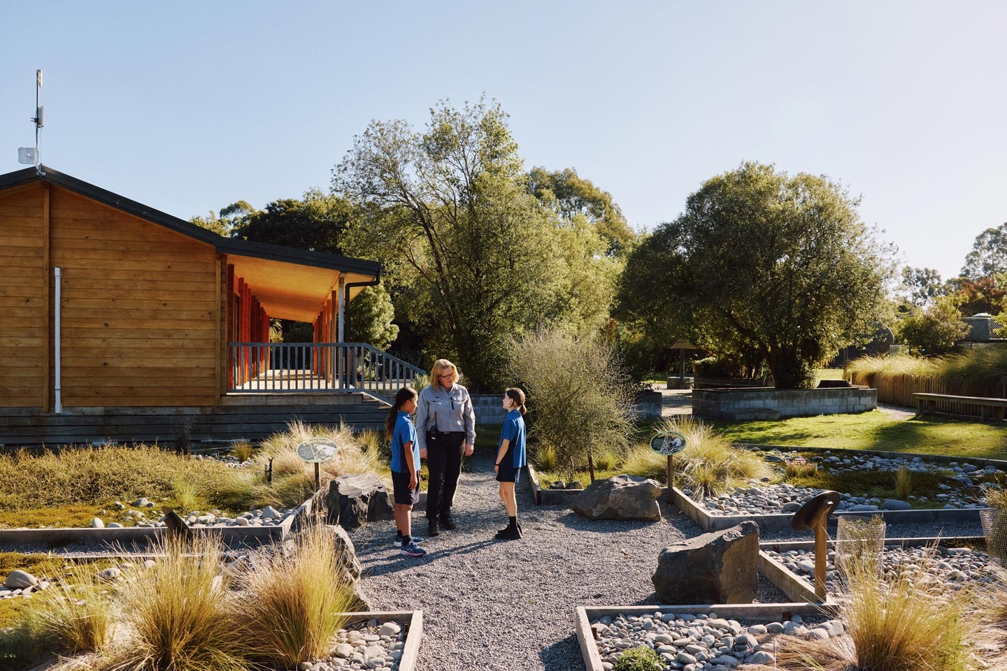 Visitors walking through a native garden past a wooden building