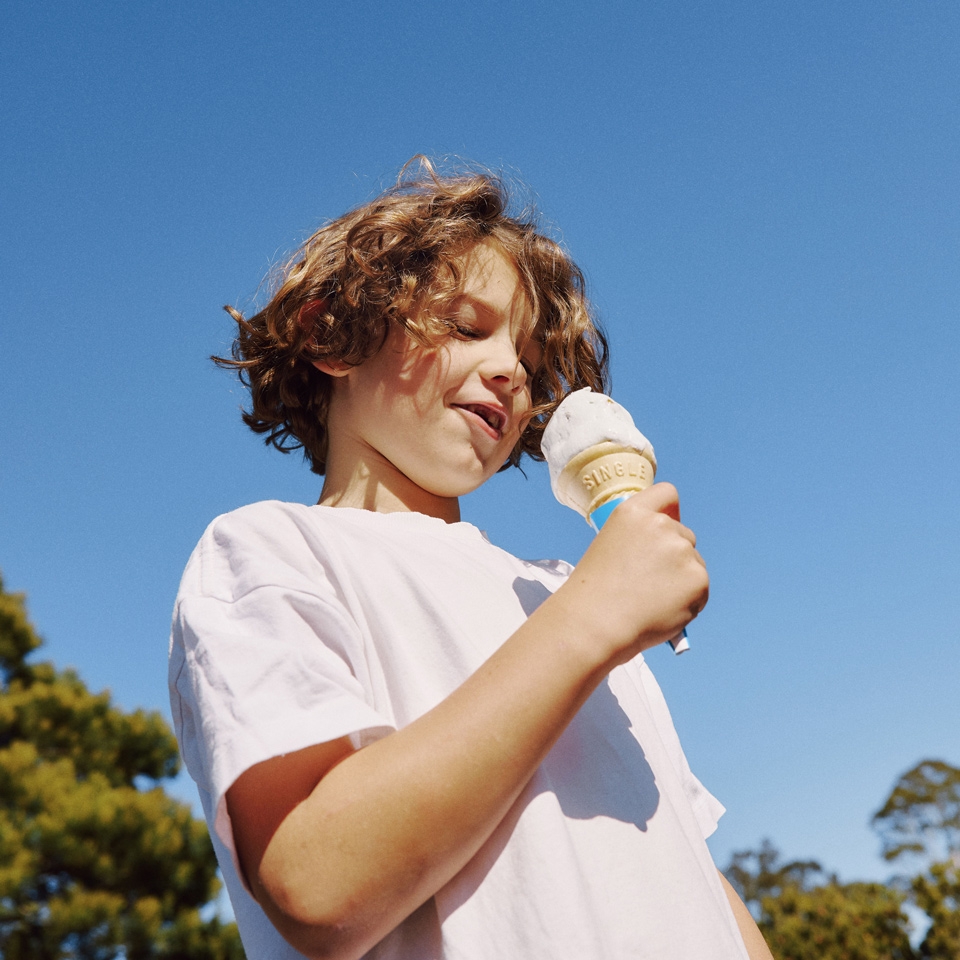 A boy eating an ice cream in the sun