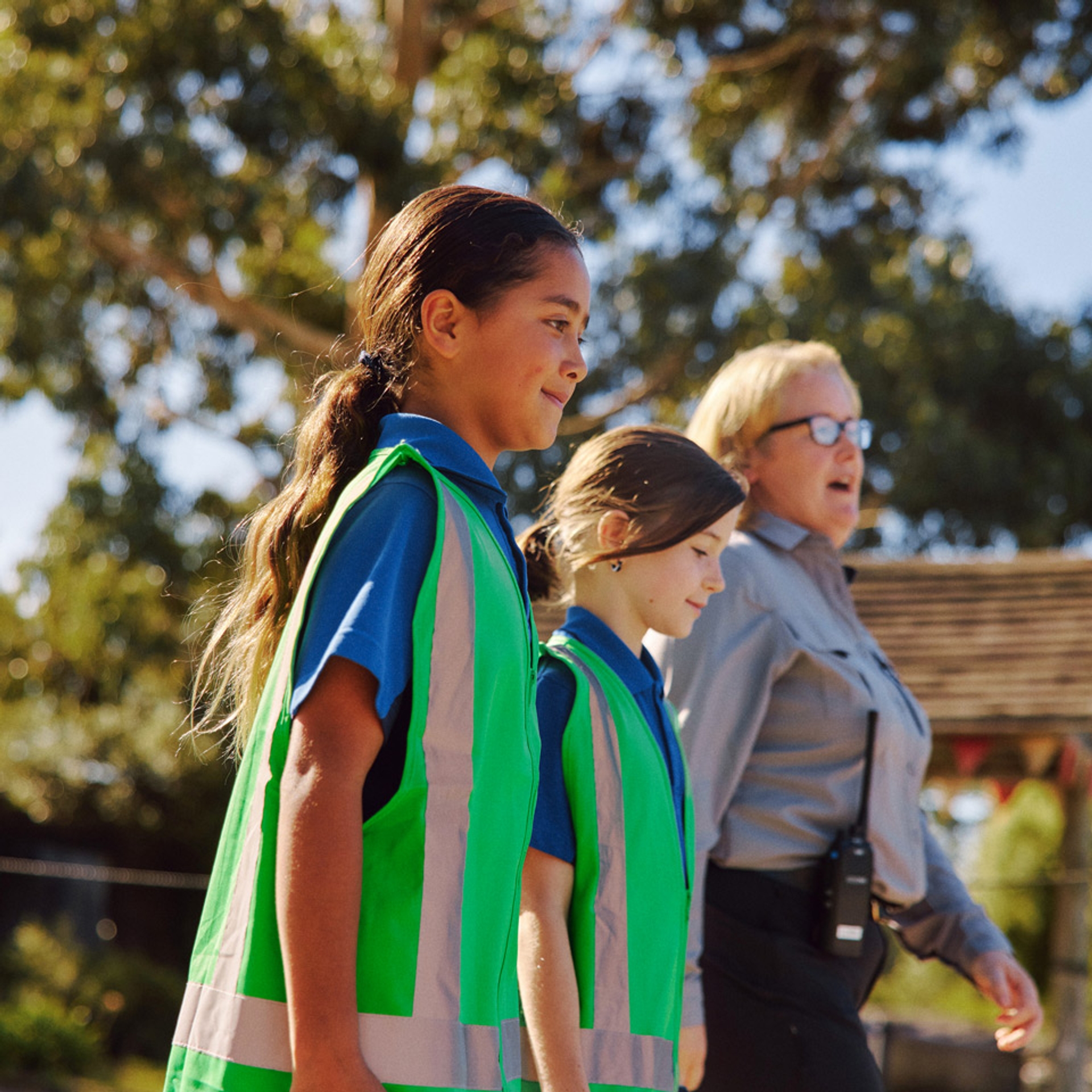 Two students in hi-vis vests walking with an Orana staff member