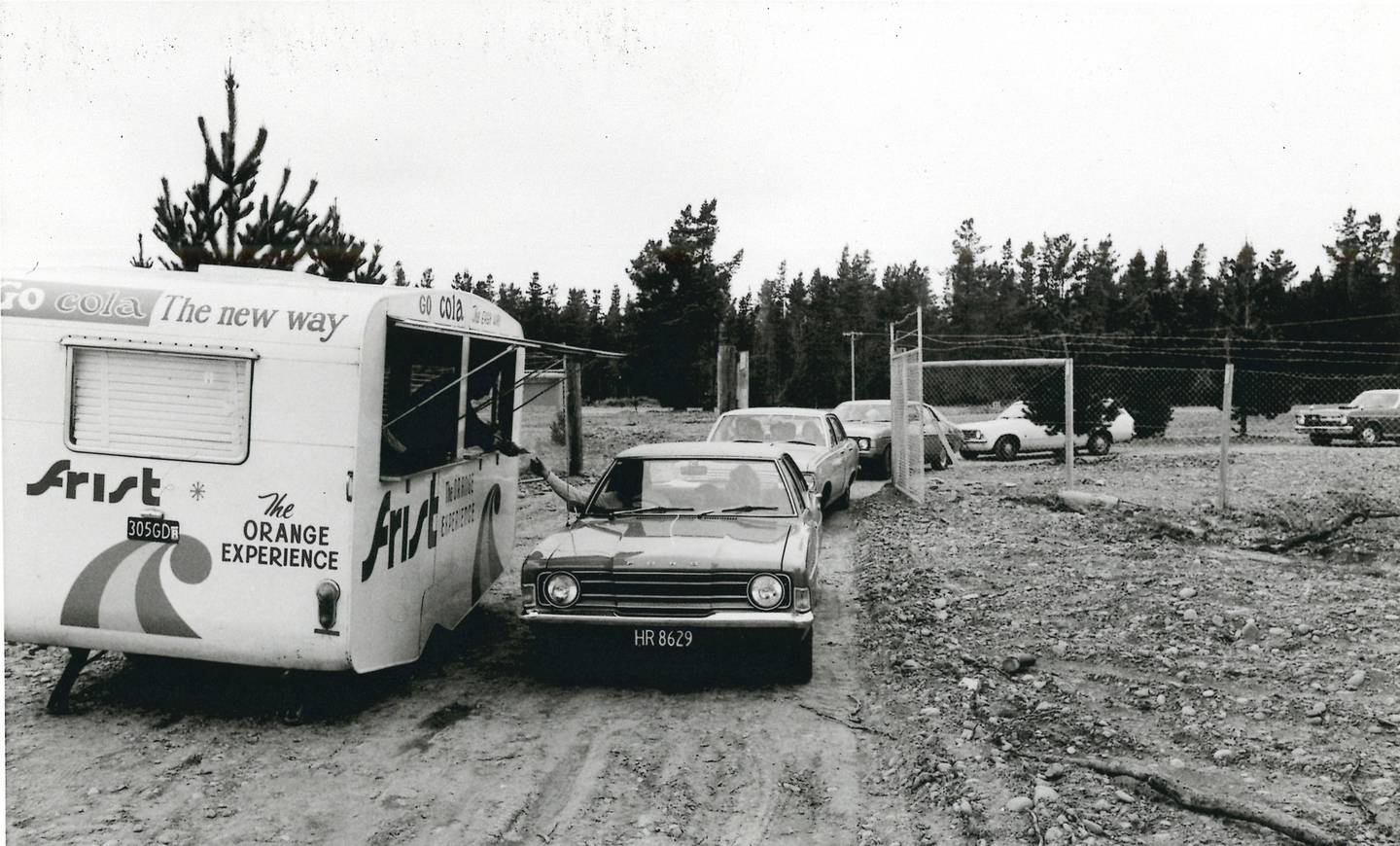 A black and white photo from opening day showing a car pulling up beside a caravan to purchase a ticket