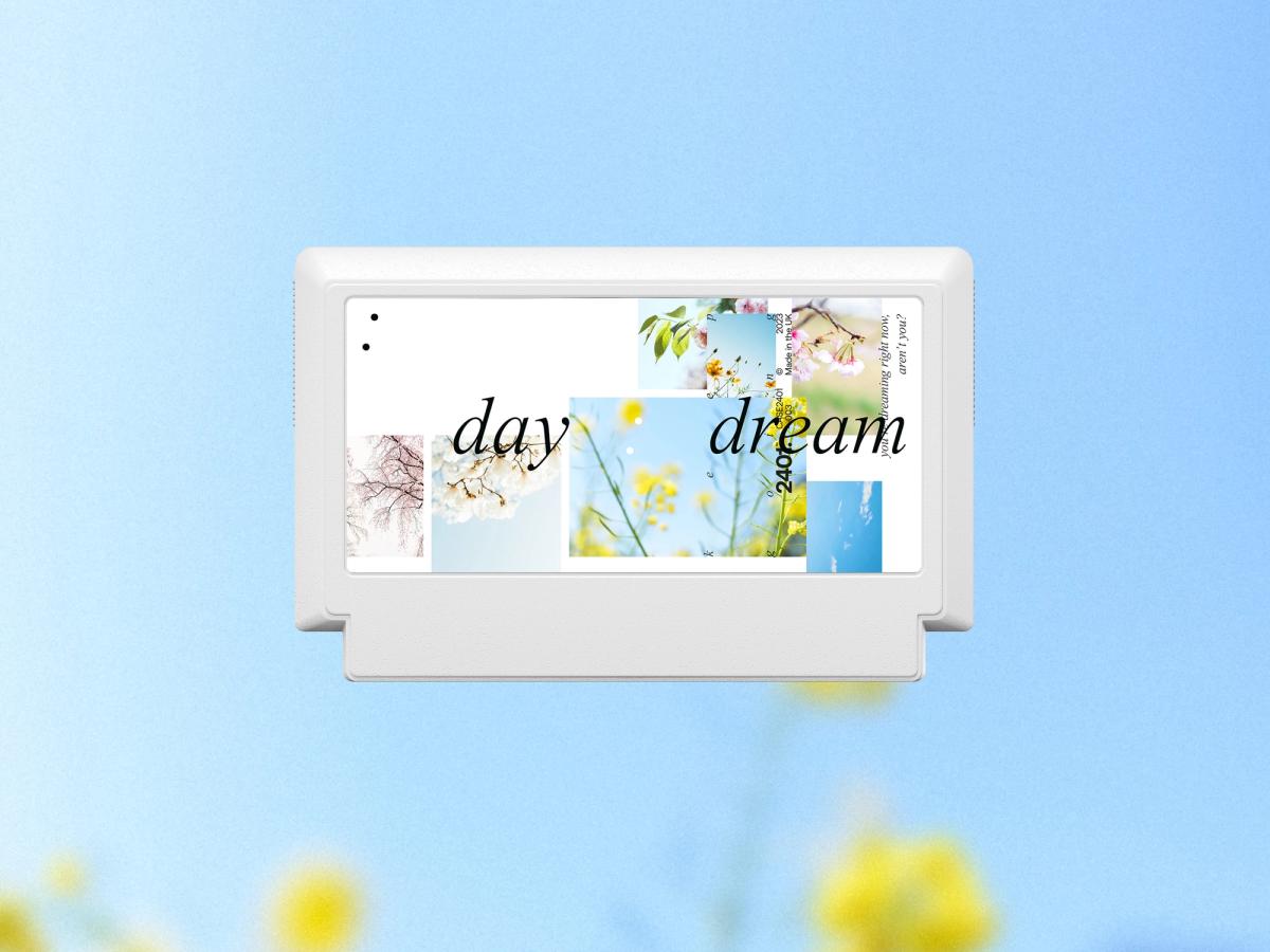 White Famicom game cartridge for “daydream,” layering spring-flower photographs with expressive italic typography against a blue sky and yellow blossoms.