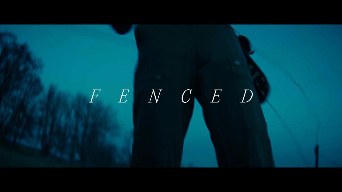 “Fenced” appears in widely spaced white serif letters over a blue-green outdoor shot of a person.