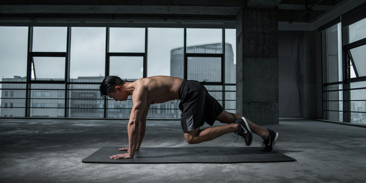 A man doing a workout on a yoga mat in an industrial gym.