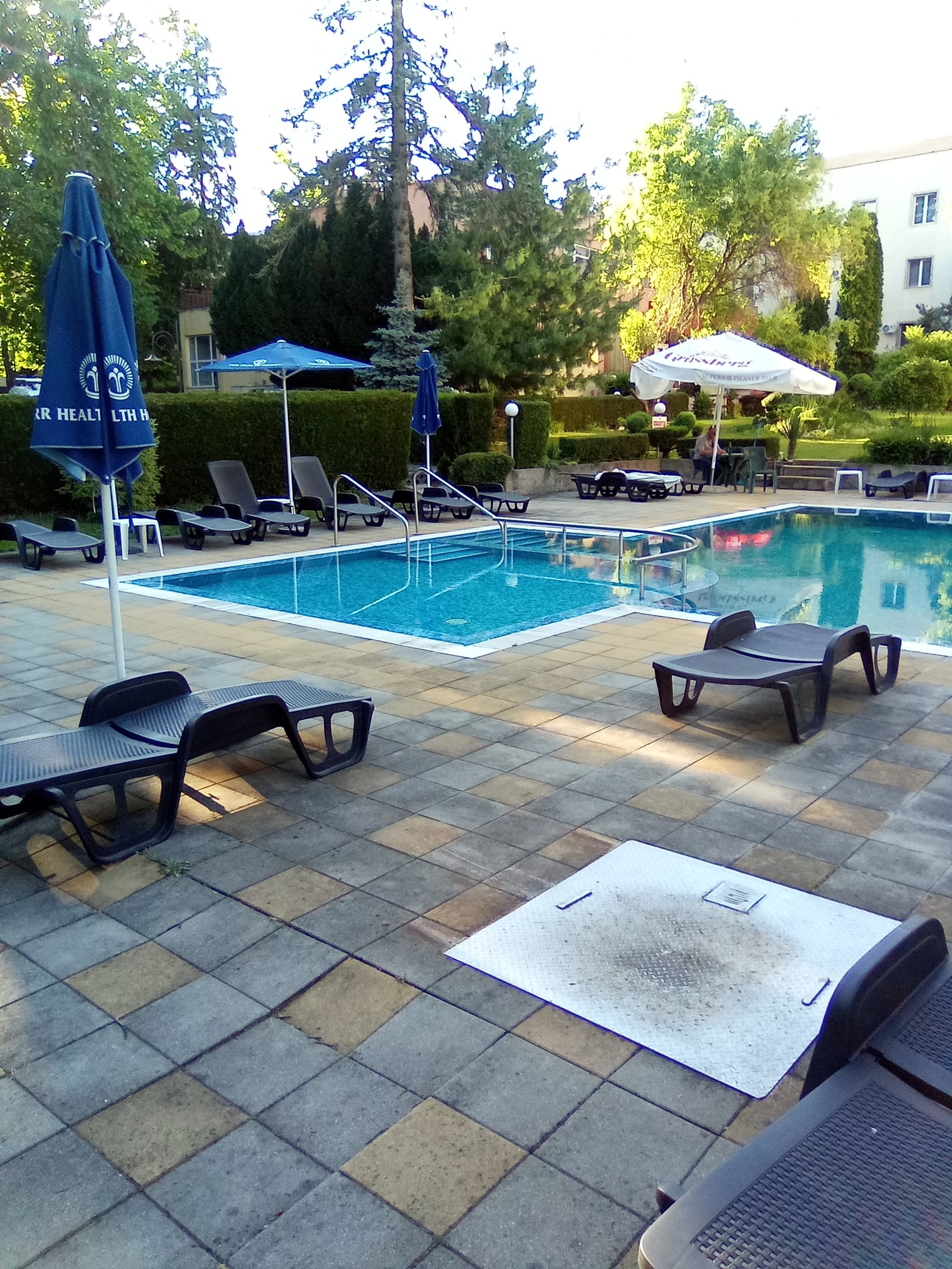 Pool terrace with black sunbeds, blue and white umbrellas and an outdoor pool