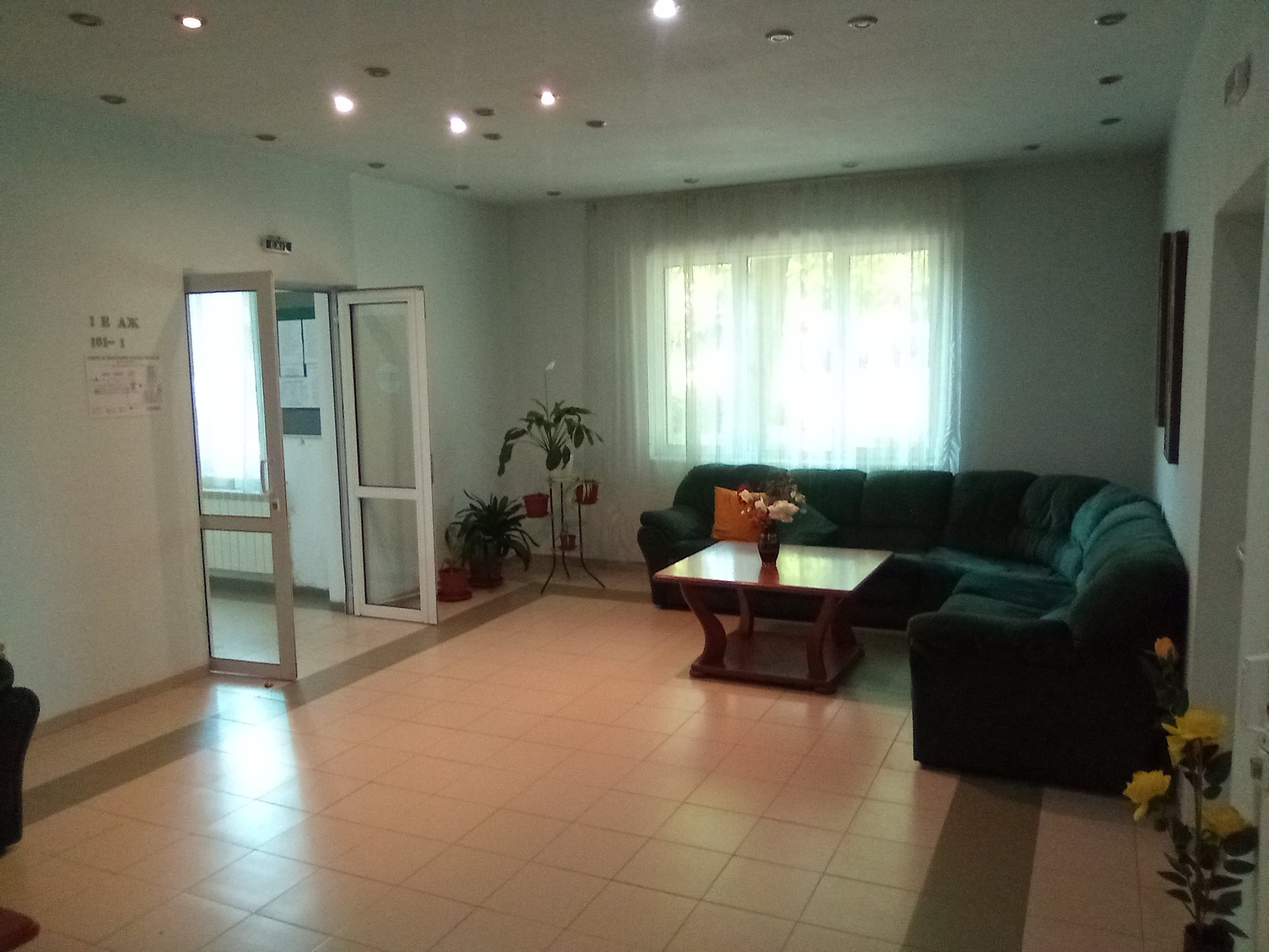 Lobby lounge with a green corner sofa, a coffee table and curtained windows