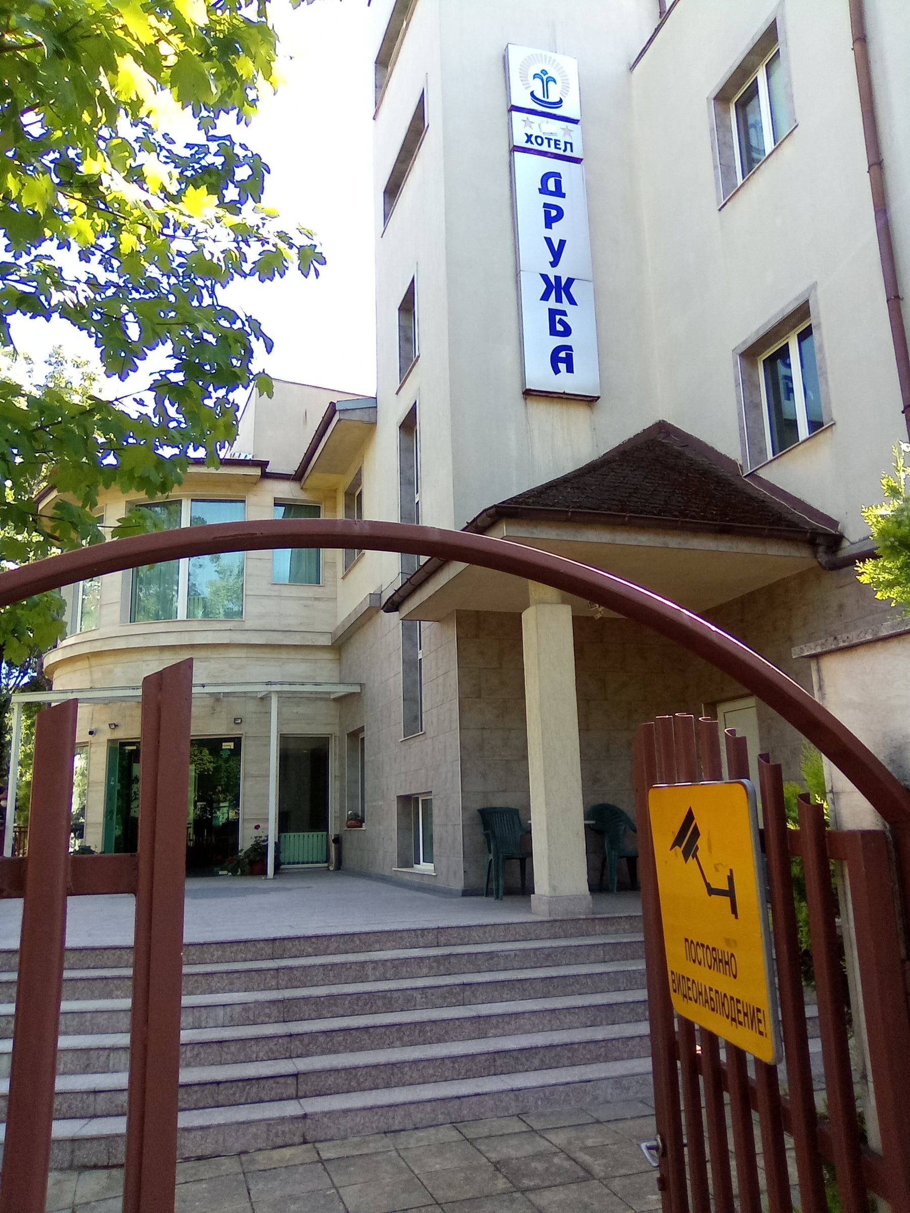 Hotel entrance with steps, a canopy and a vertical "Druzhba" sign on the facade