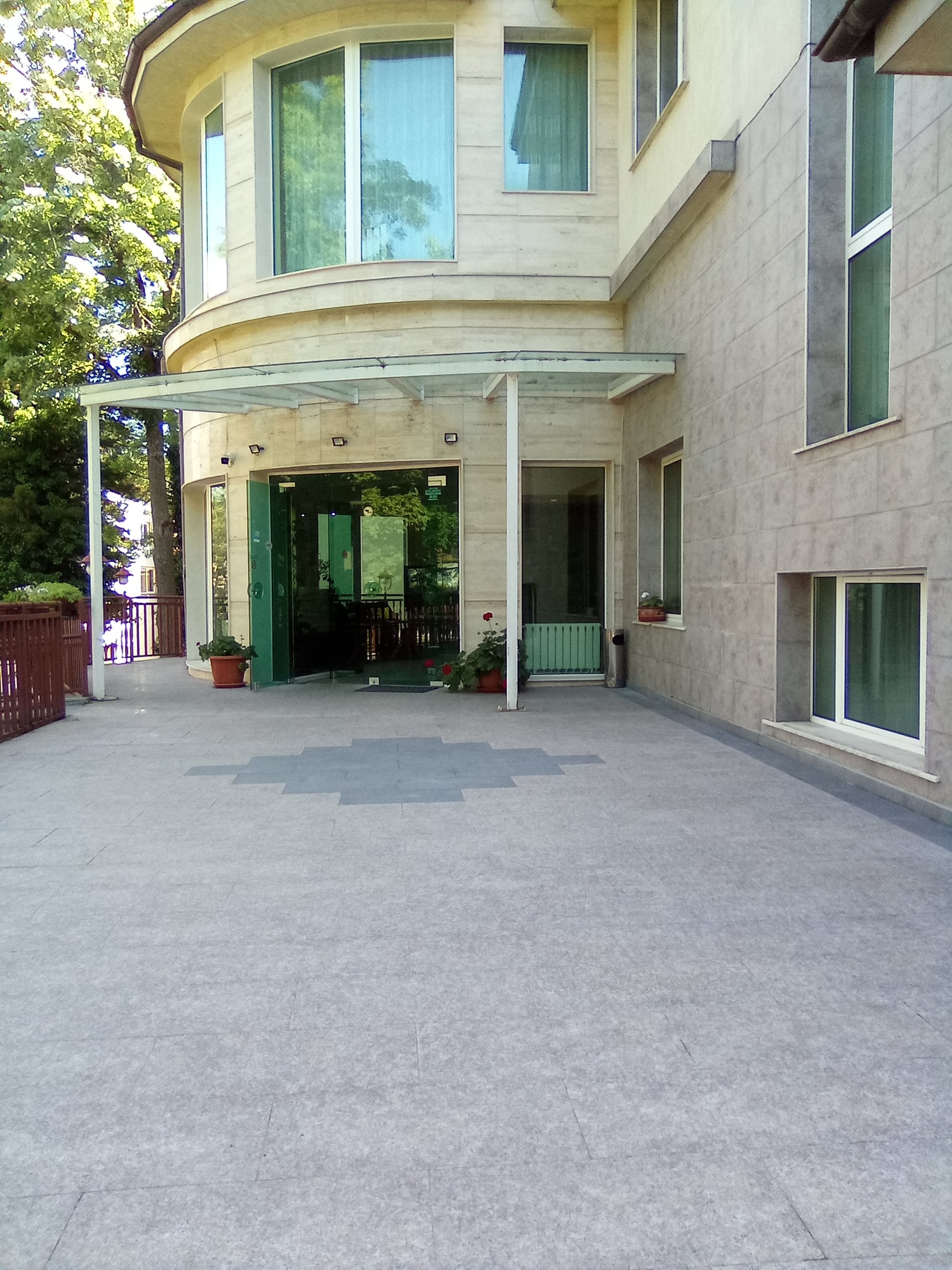 Rounded glass-fronted hotel wing with a covered entrance and a paved terrace