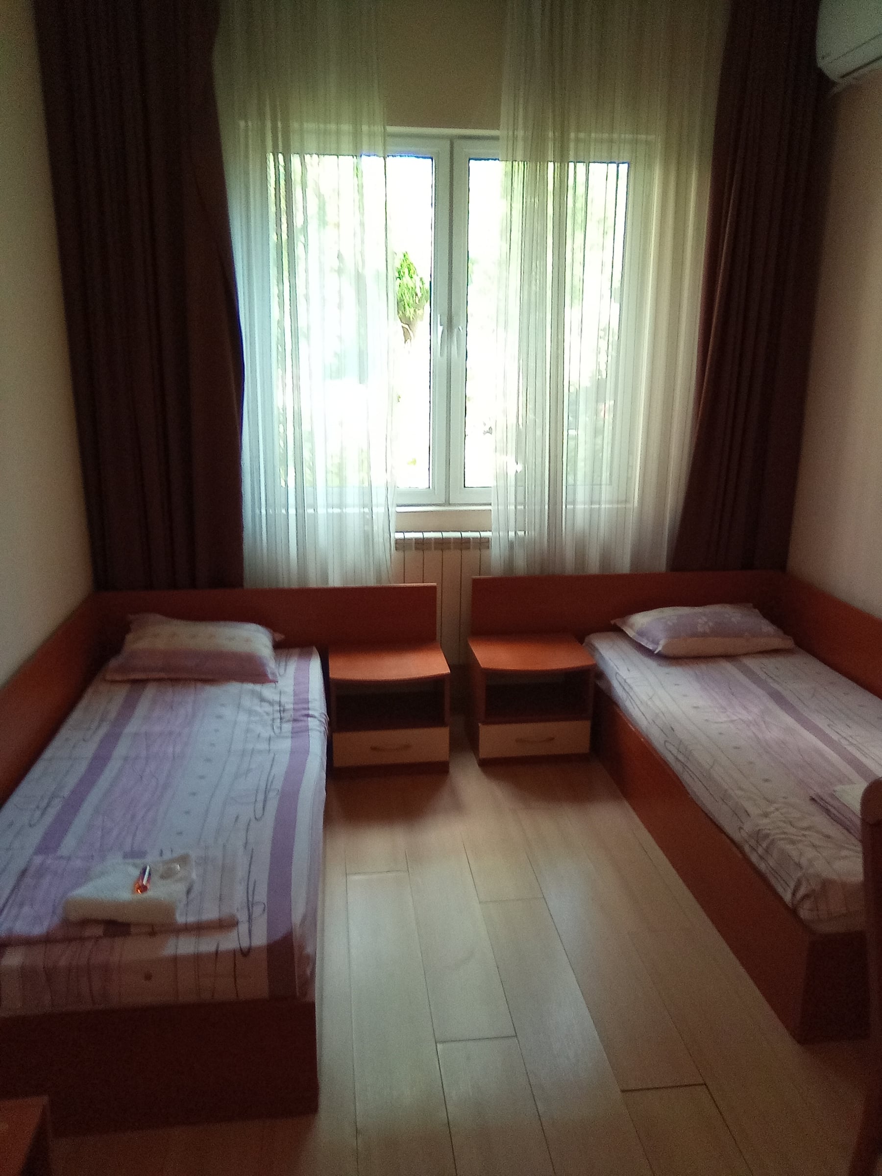 Twin room with two single beds, wooden floor and a window with sheer curtains