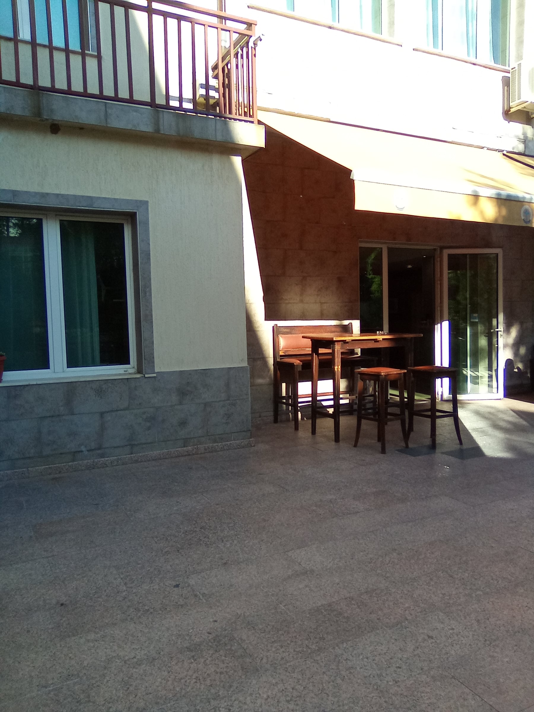 Small outdoor seating area with a table and chairs beside a hotel building