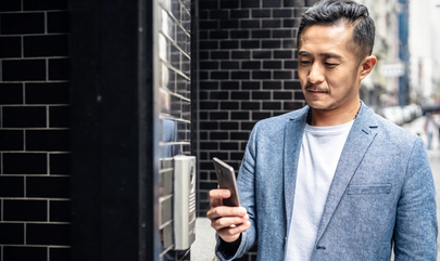 man outside building holding phone next to access reader