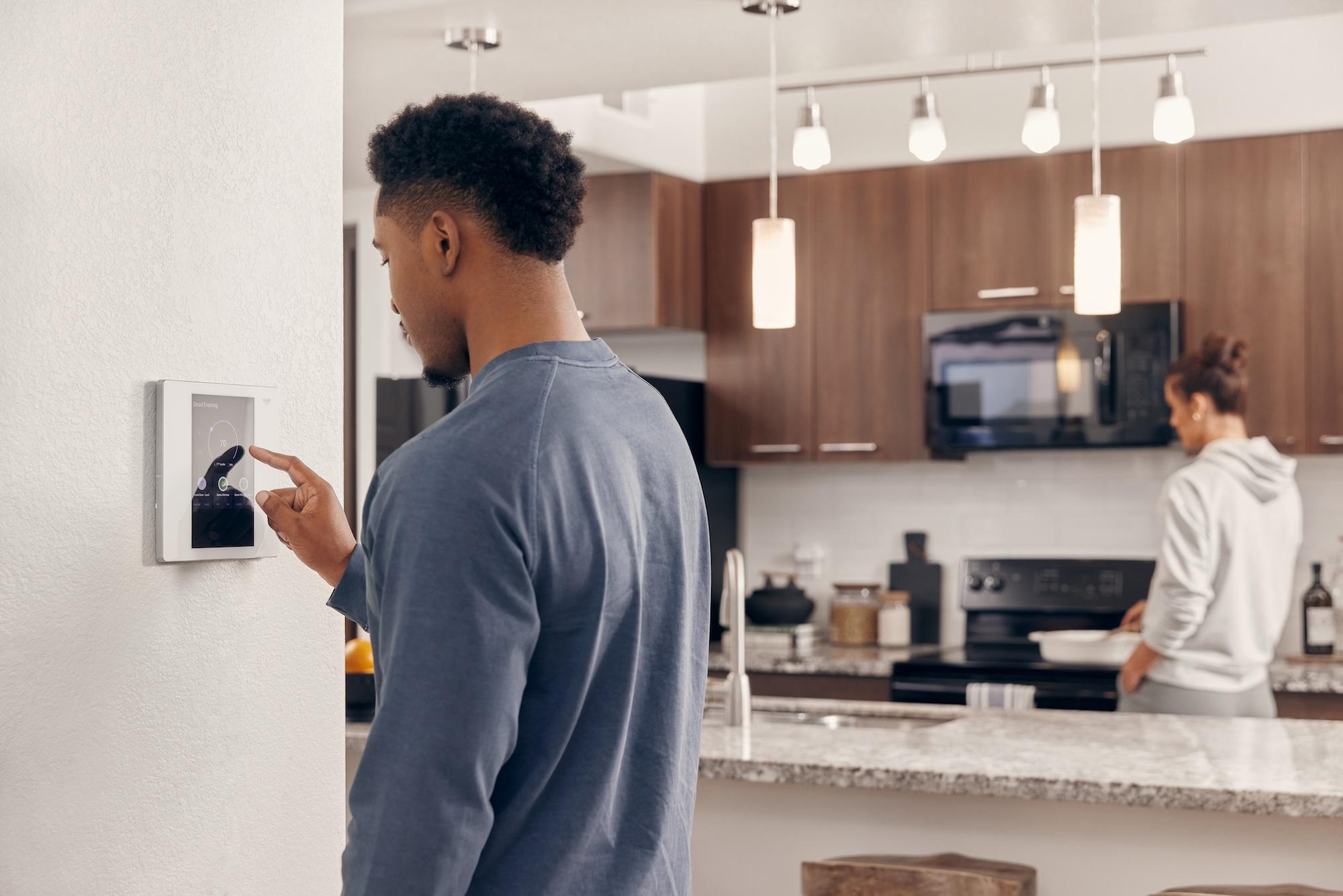Man adjusting Smart Apartment controls at a hub in his kitchen