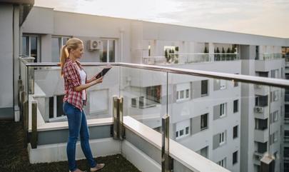 woman looking at tablet on apartment balcony