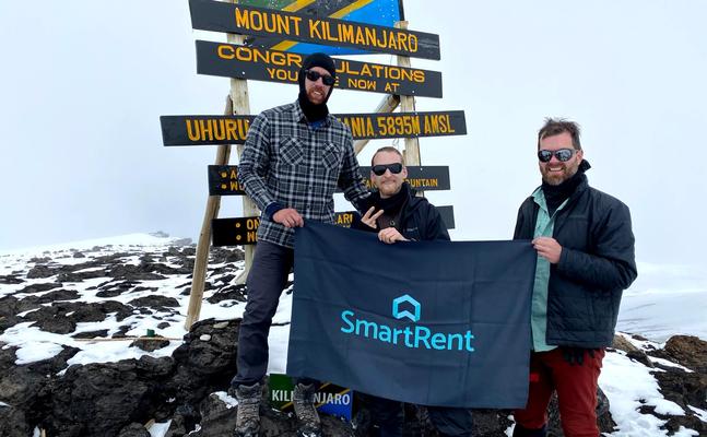 SmartRent trekkers holding up SmartRent flag at peak of Kilimanjaro