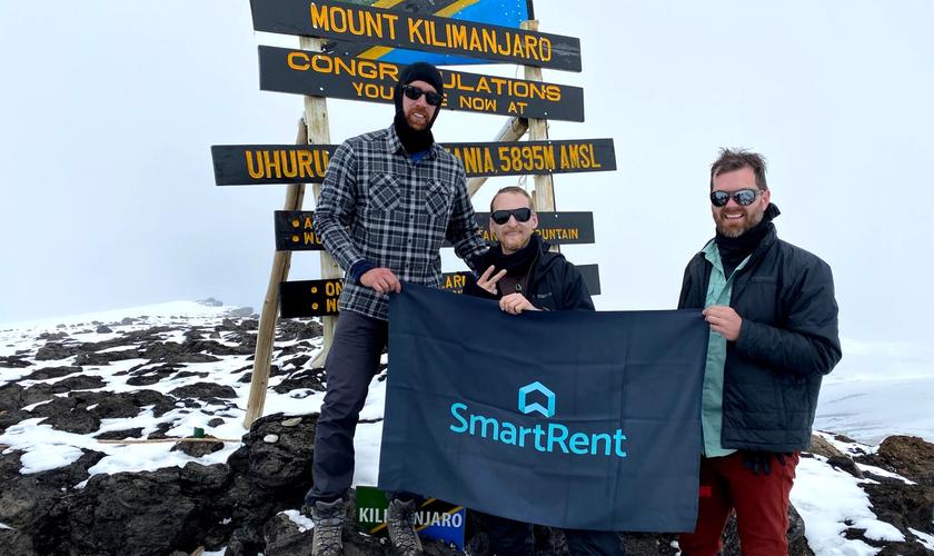 SmartRent trekkers holding up SmartRent flag at peak of Kilimanjaro