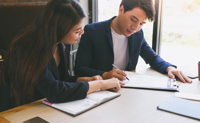 two people looking a documents on a desk together