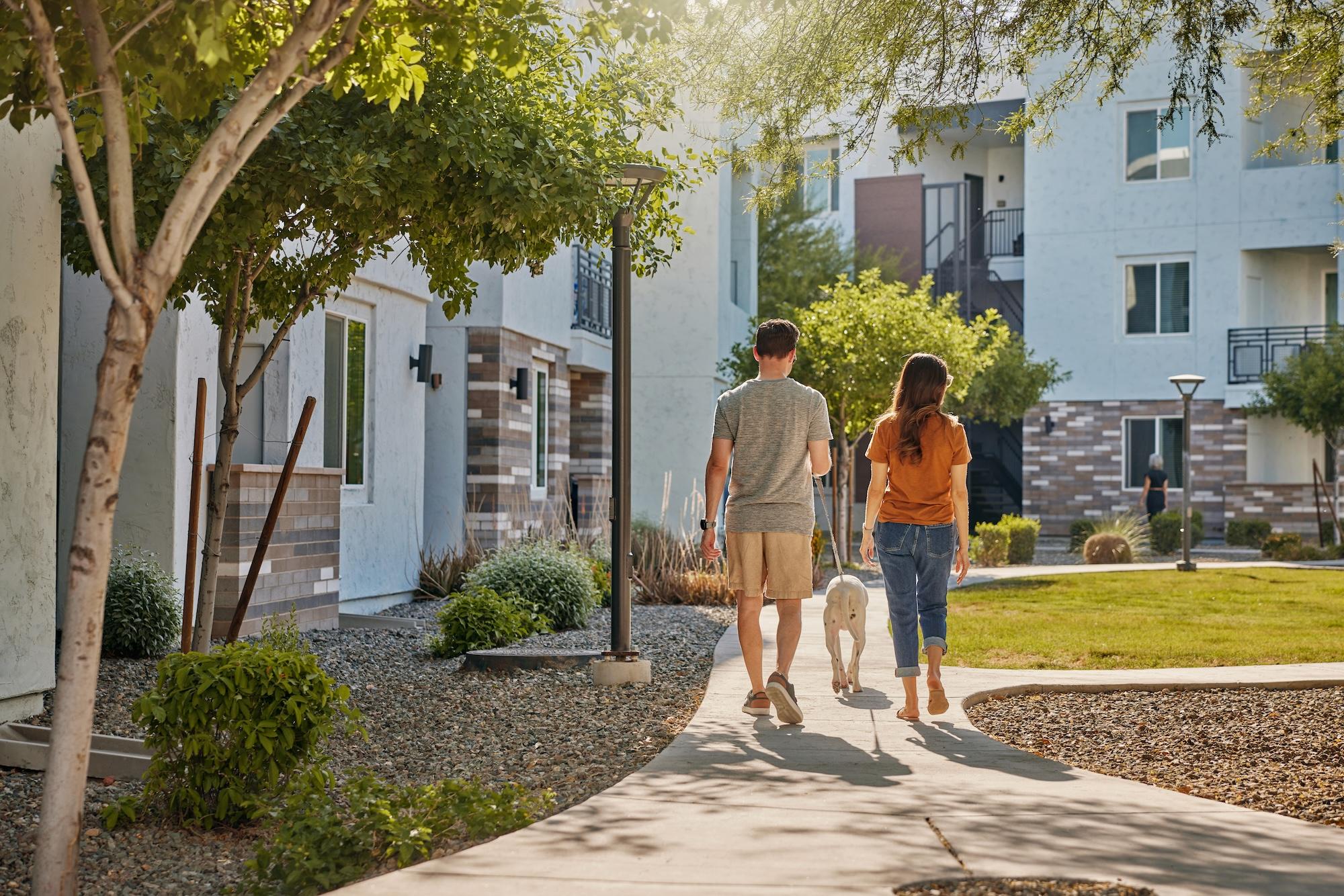Couple walking dog in courtyard