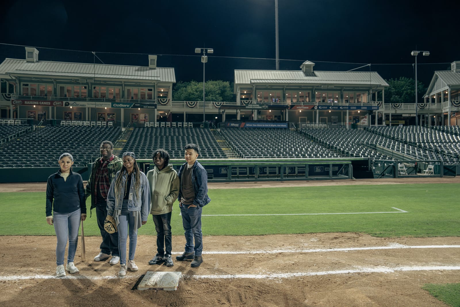 Group standing together on a stadium field at night
