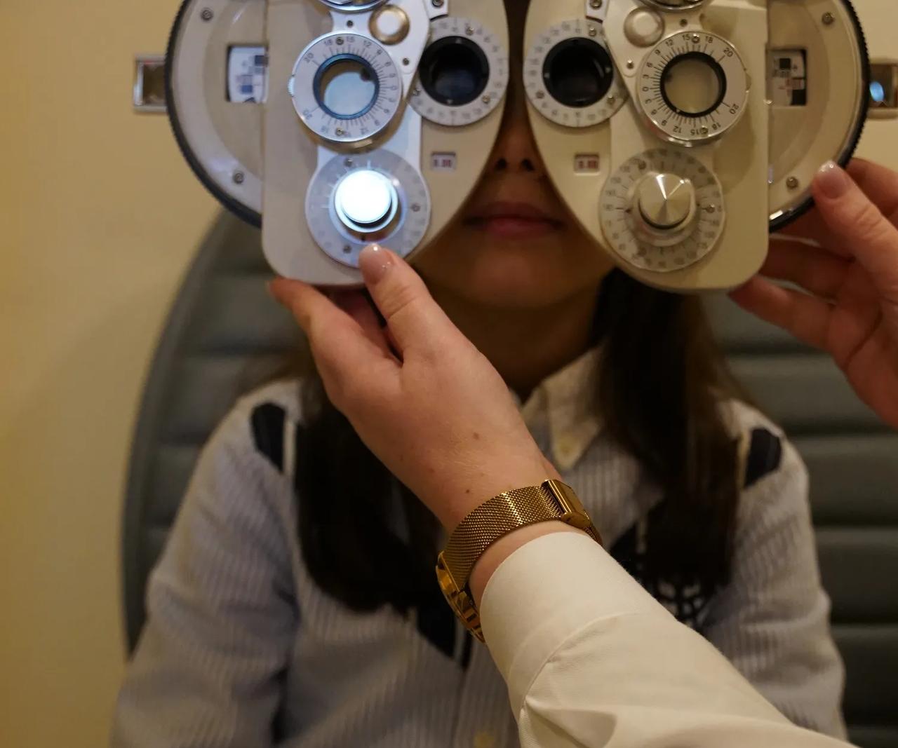 Optometrista a ajustar foróptero durante consulta