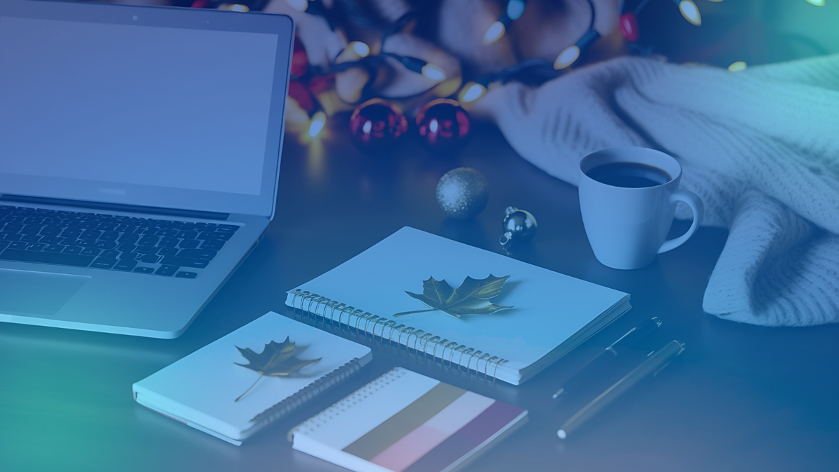 A cozy setup of a cup of coffee, a book, and a laptop on a wooden table.