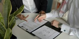 Drie professionals bespreken een offerte aan tafel