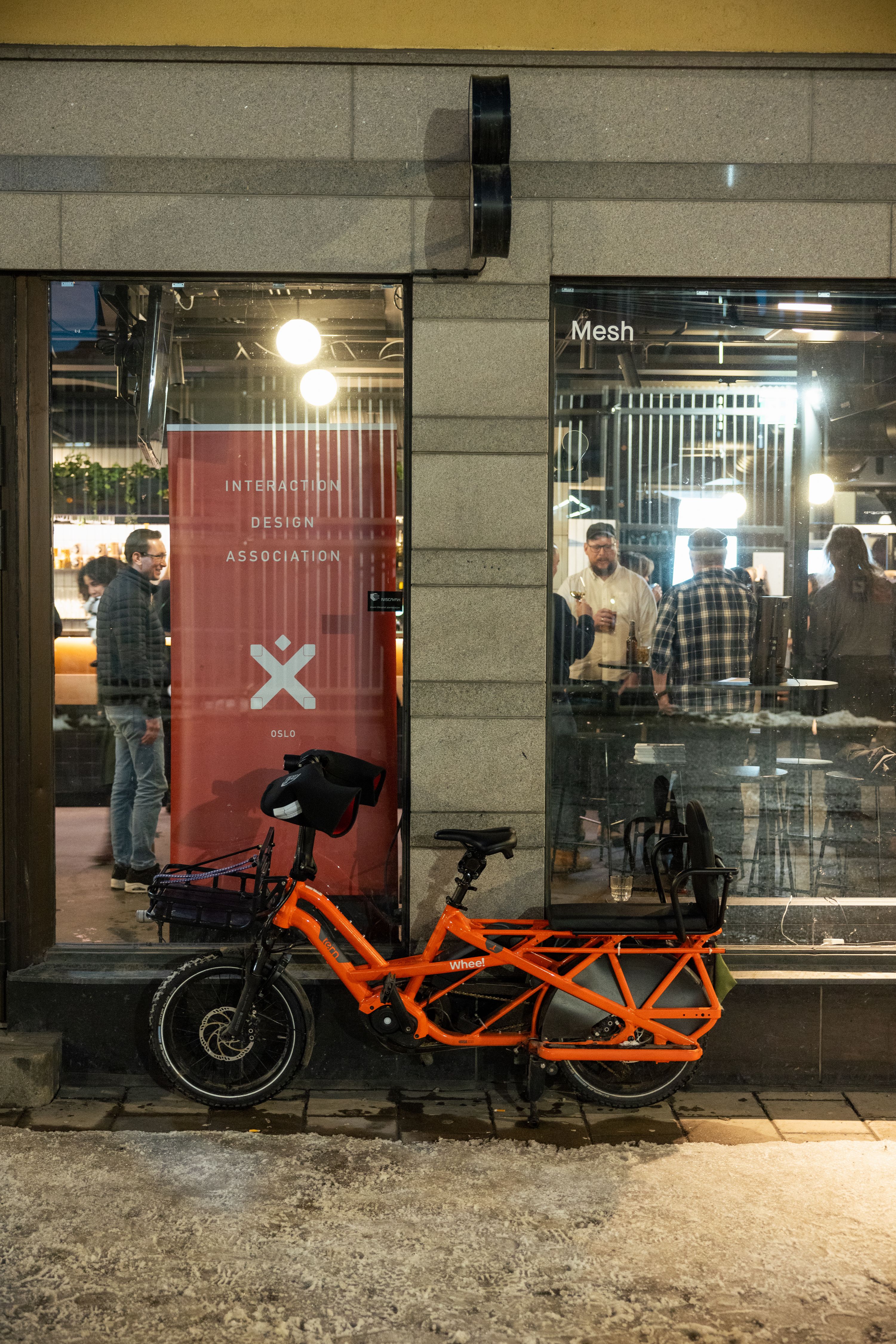A Tern electric midtail bike stands parked outside MESH Youngstorget. Behind the bike, IxDA Oslo's banner is visible.