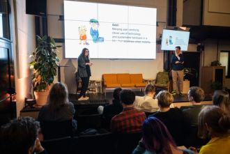 Two people standing on a stage in front of people