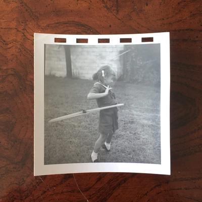 A black-and-white photo of a little girl in white ankle socks spinning a hula hoop.