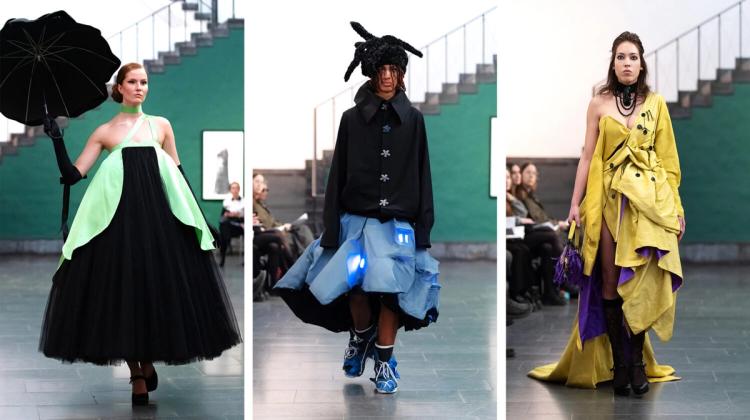Tre modeller på catwalk: en i svart tyllklänning med grönt och svart paraply, en i svart skjorta och blå kjol, en i gul draperad klänning.