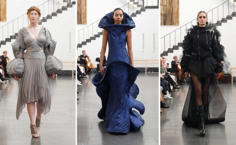 Tre modeller på catwalk: en i grå plisserad klänning med ballongärmar, en i blå vadderad klänning med hög krage, en i svart fjäderjacka och tyllkjol.