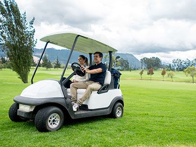 Man and woman driving golf cart on golf course