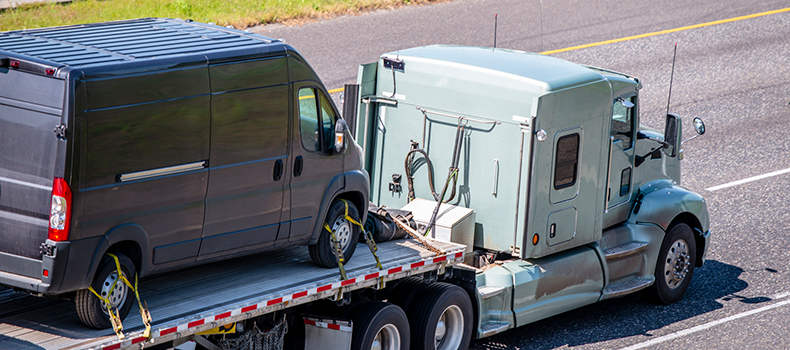 Large van on flatbed trailer truck for transport