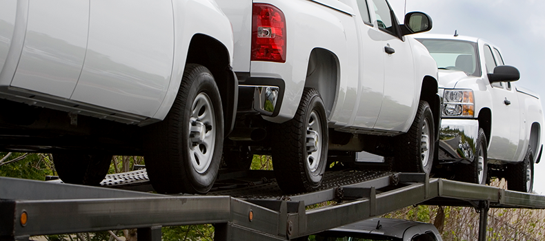 white trucks on open trailer help keep car shipping costs down