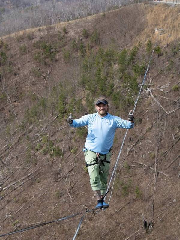 A professional highliner walking a slack line across the valley of the SkyBridge.