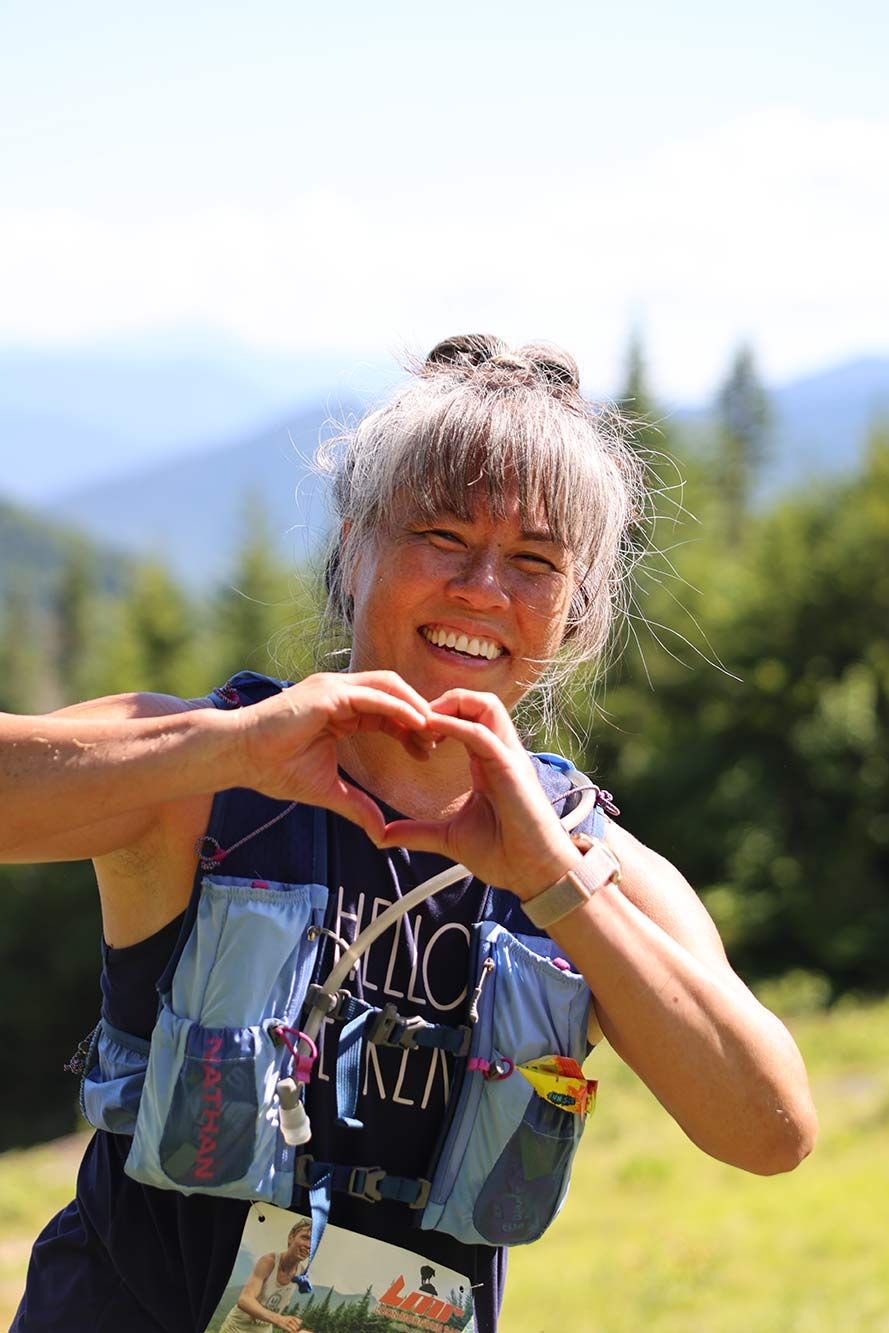 female racer smiling at the camera, making heart shape with hands