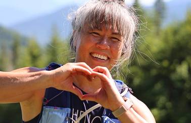 female racer smiling at the camera, making heart shape with hands