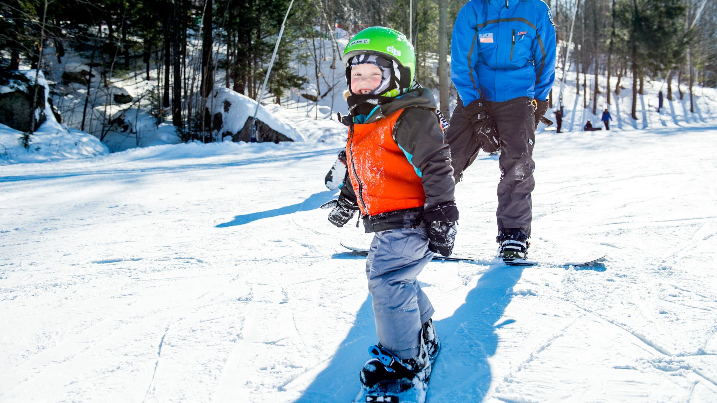 girl learning to snowboard with a coach
