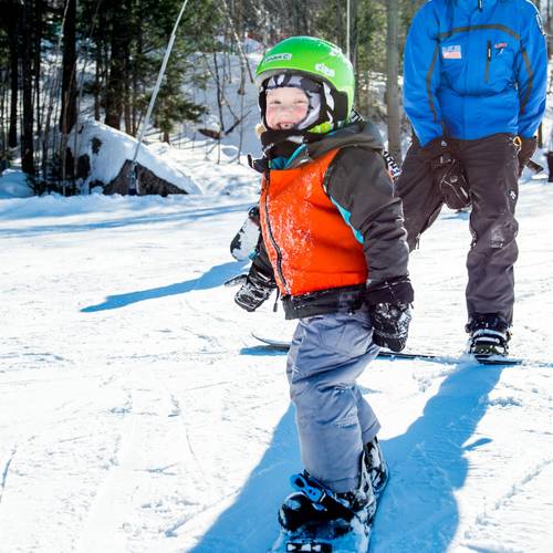 girl learning to snowboard with a coach