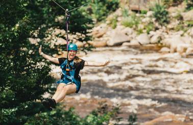 girl ziplining across the river