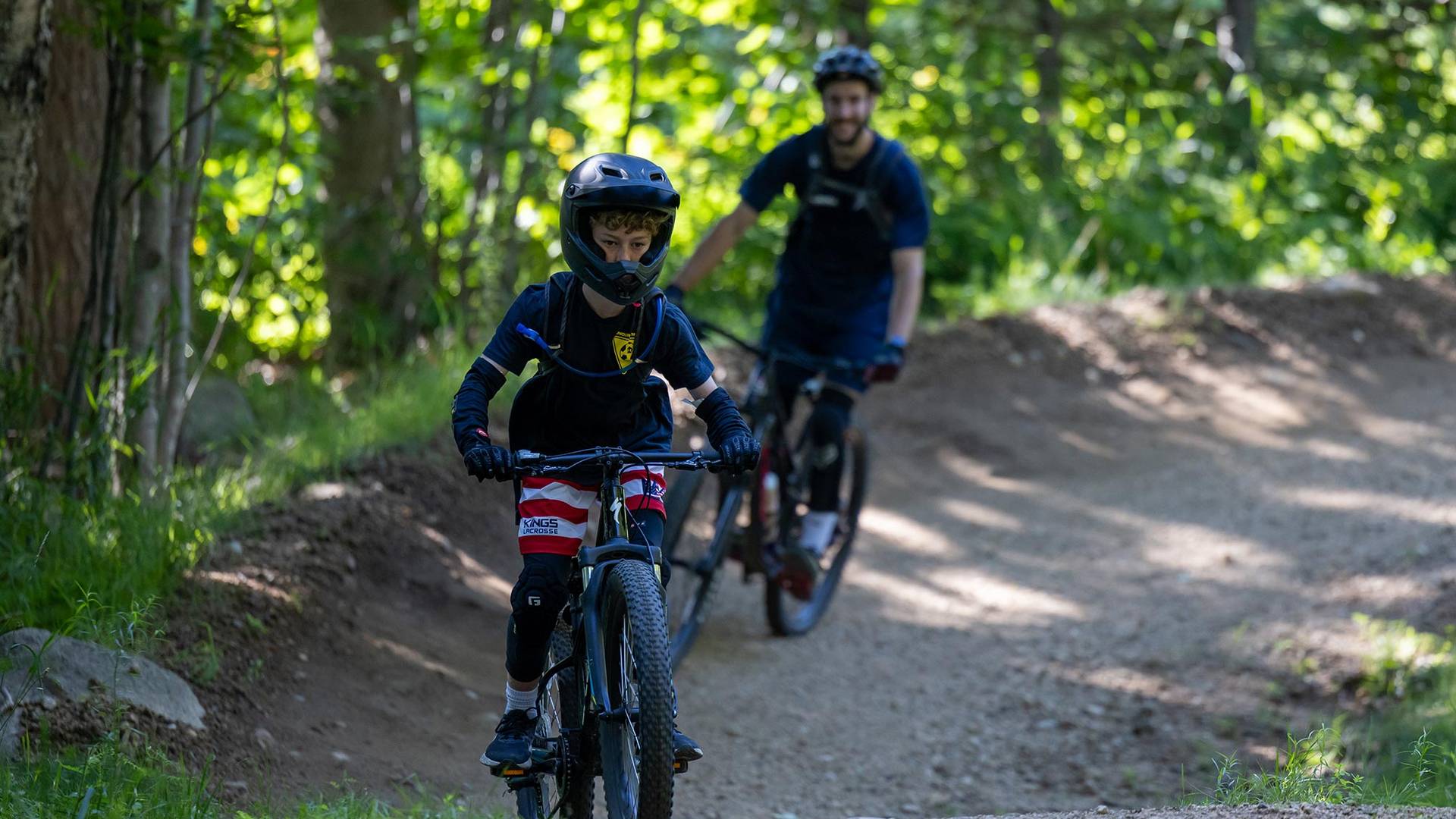 young boy camper riding on trail with instructor